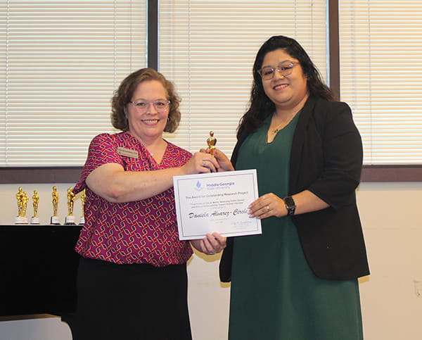 Daniela Alvarez-Circle (right) receives the Outstanding Research Project for Media Ethics Award from Dr. Cindy Montgomery, Assistant Professor of Media and Communication.